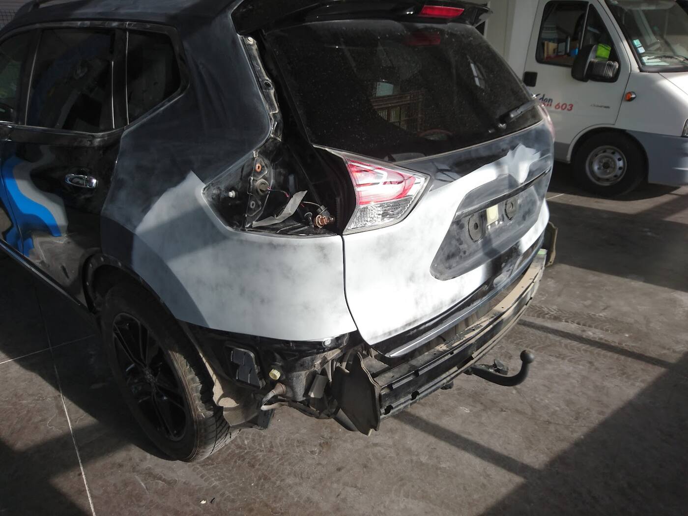 Arrière gauche d'un Nissan X-Trail noir à l'arrivée : aile et bouclier abîmés, pièces déposées