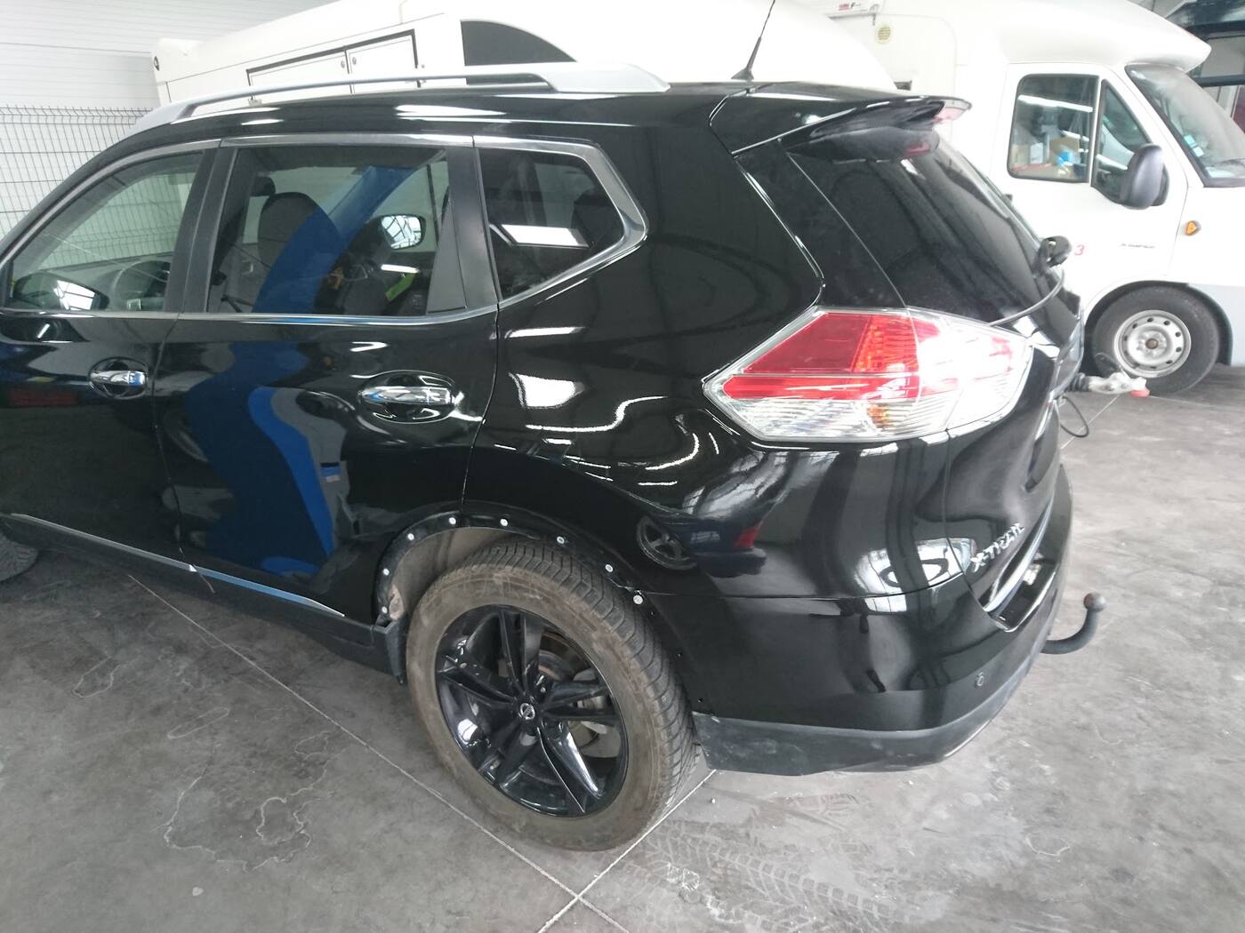 Le Nissan X-Trail noir repeint et remonté, vu de trois quarts arrière dans l'atelier